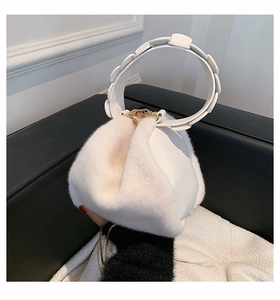 Close-up of white plush handbag featuring geometric round handle and gold hardware