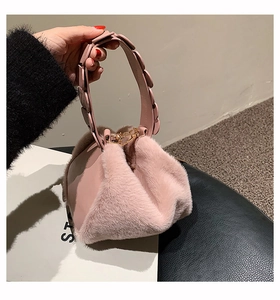 Detail of pink faux fur handbag showing floral leather handle and gold chain strap