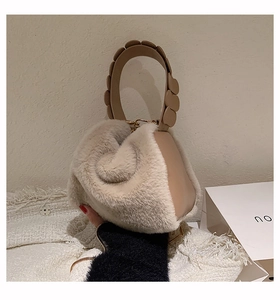 Detail of plush faux fur handbag featuring layered circular handles and beige texture