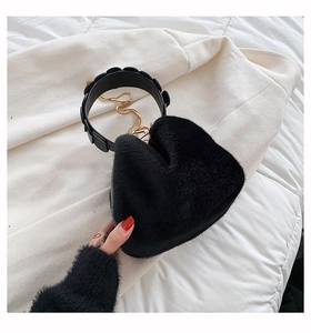 Detail of black heart shaped faux fur handbag with plush texture and gold chain strap