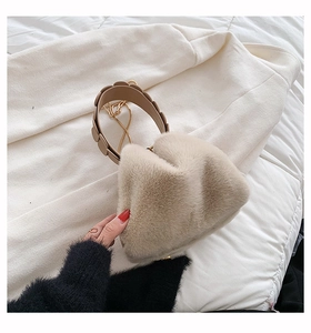 Close-up of plush faux fur handbag featuring a wide brown leather handle and gold chain strap