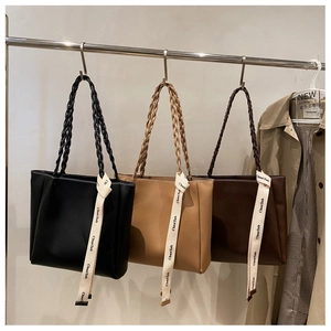 Trois sacs cabas avec anses tressées en noir, beige et marron sur un présentoir