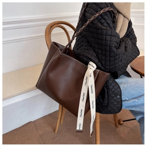Détail du sac cabas marron foncé avec surpiqûres blanches et une poignée tressée élégante