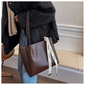 Détail du cabas marron foncé avec poignée tressée et ruban en toile avec logo noir