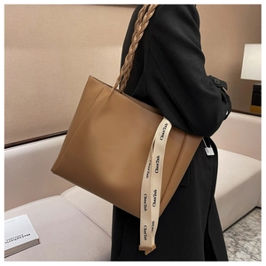 Détail d'un sac cabas en similicuir marron avec poignée tressée et sangle décorative