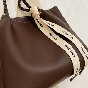 Gros plan du sac cabas marron montrant la texture du cuir et la poignée tressée