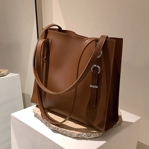 Minimalist brown leather tote bag with silver metal eyelets and double shoulder straps