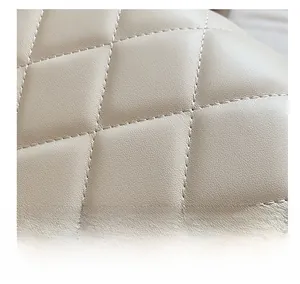 Macro shot of precise computer-stitched diamond quilting on beige leather bag surface