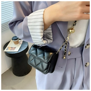 Detail of black quilted mini bag with adjustable gold ball chain and glossy finish