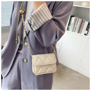 Detail view of cream quilted PU leather mini bag with golden chain strap on model