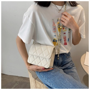 Close-up of white quilted crossbody bag with golden chain strap and round metal adjuster
