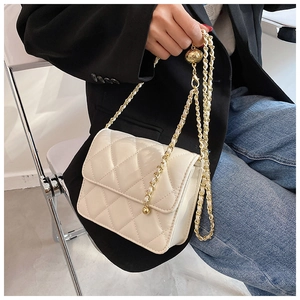 Detail of white quilted crossbody bag with adjustable gold ball chain strap on a model