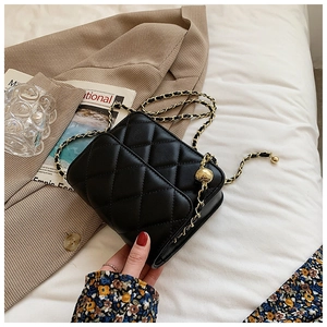 Close-up of black quilted leather chain bag with gold metal ball adjustment buckle