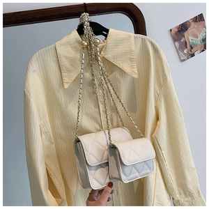 Close-up of white quilted mini bags set with golden metal and leather chain strap