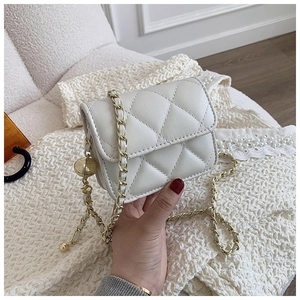 Detailed macro view of quilted cream leather texture and gold chain strap with ball charm