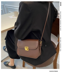 Détail d'un petit sac bandoulière en cuir marron vintage avec fermoir doré sur modèle