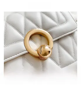 Close-up of elegant V-quilted white leather bag with a luxury round golden hardware clasp