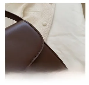 Vue macro des coutures soignées et de la boucle en métal doré sur le sac en cuir marron
