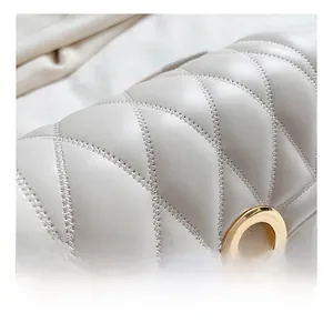 Detail of white quilted leather bag showing fine stitching and round gold metal lock