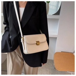 Détail d'un petit sac bandoulière en similicuir crème avec un fermoir doré rectangulaire