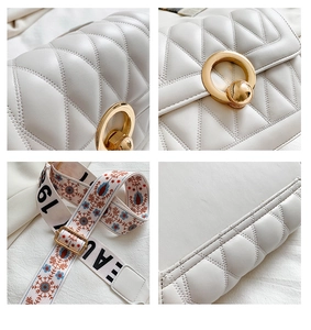Detail of white quilted crossbody bag with golden ball lock and floral embroidery strap