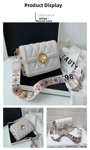 Close-up of white quilted square bag with gold round lock and patterned wide strap