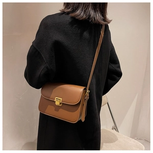 Détail du sac bandoulière en similicuir marron avec boucle dorée sur un manteau en laine