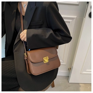 Détail d'un petit sac bandoulière marron vintage avec boucle dorée et texture fine