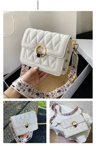 Detail of white quilted crossbody bag with golden deer lock and ethnic printed strap