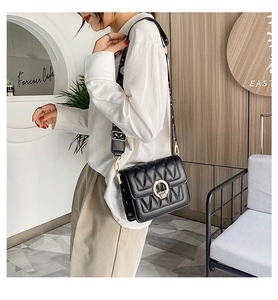 Detail of black quilted shoulder bag featuring gold circular lock and geometric strap