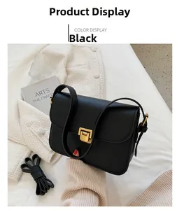 Détail du sac bandoulière noir avec boucle dorée carrée et sangle réglable amovible