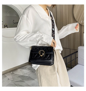Detail view of black square crossbody bag with quilted texture and floral wide strap
