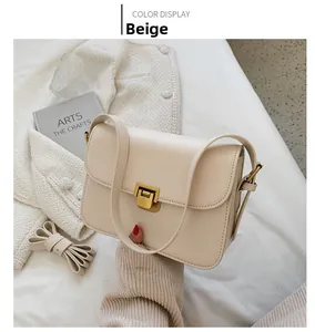 Détail d'un sac à bandoulière beige en cuir avec un fermoir doré rectangulaire