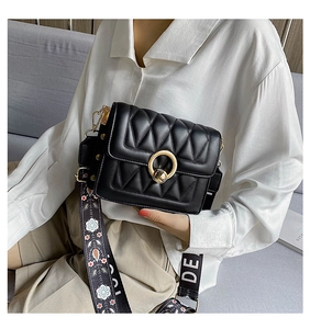 Detail of black quilted shoulder bag with gold ring buckle and vintage jacquard strap