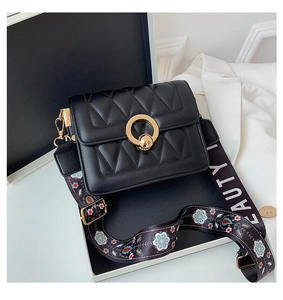 Detail of black quilted crossbody bag with golden ring clasp and floral beauty wide strap