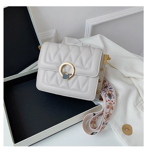 Detail of crossbody bag featuring gold deer buckle and ethnic embroidered wide strap