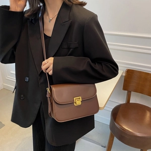 Sac bandoulière marron rétro avec boucle dorée sur mannequin pour style minimaliste