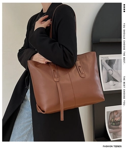 Detailed side view of large caramel brown tote bag worn on shoulder by a model