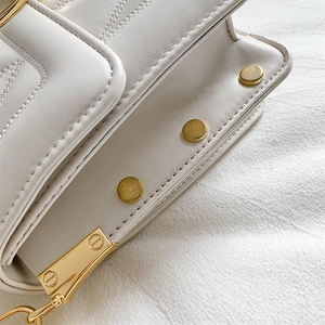 Chic cream quilted crossbody bag featuring elegant chevron stitching and gold stud details