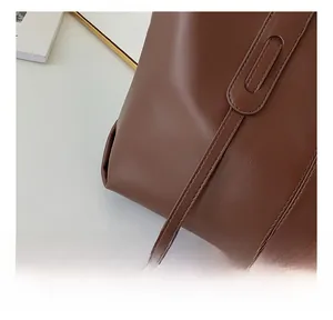 Detailed view of the handcrafted stitching and shoulder strap on the brown leather tote bag