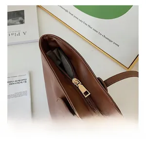 Detail view of a brown tote bag featuring a smooth gold zipper and patterned lining