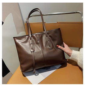 Close-up of deep brown leather tote bag with long tassel detail and elegant stitching