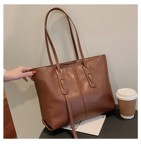 Brown large capacity tote bag with lychee texture and coffee cup on a desk