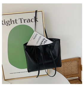 Minimalist black PU leather tote bag shown with long shoulder straps and magazine detail