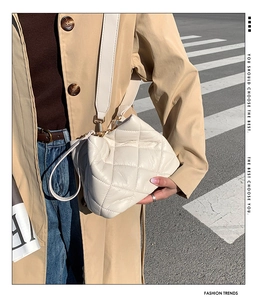 Detail of white quilted crossbody bag with golden buckle on a stylish woman