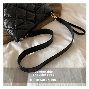 Detail of comfortable shoulder strap with gold metal hook on black quilted bucket bag
