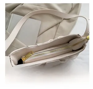 Detail of smooth gold zipper closure on beige pleated cloud bag with soft leather texture