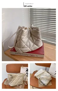 Detail of cream white quilted bucket bag with gold hardware and smooth leather finish