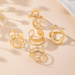 Macro detail of five minimalist gold irregular rings with smooth metallic textures