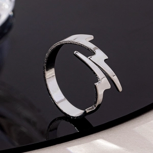 Detail of silver lightning bolt adjustable ring on a black reflective surface